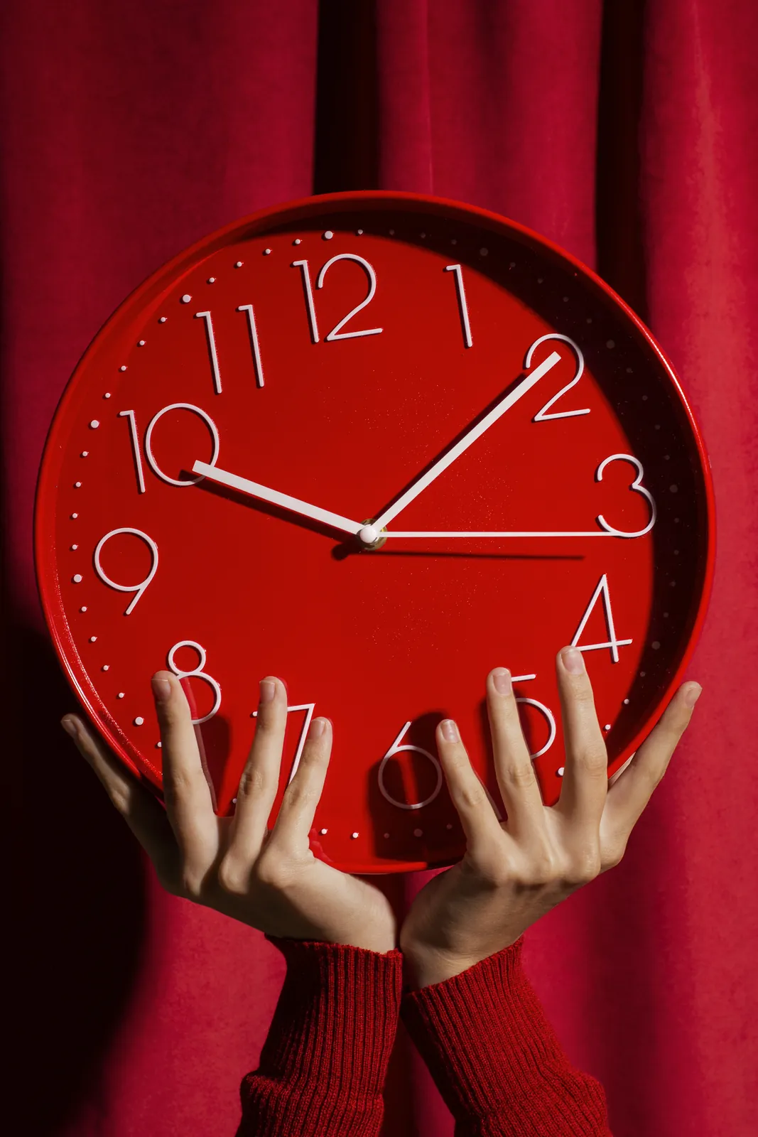Hands holding a red wall clock