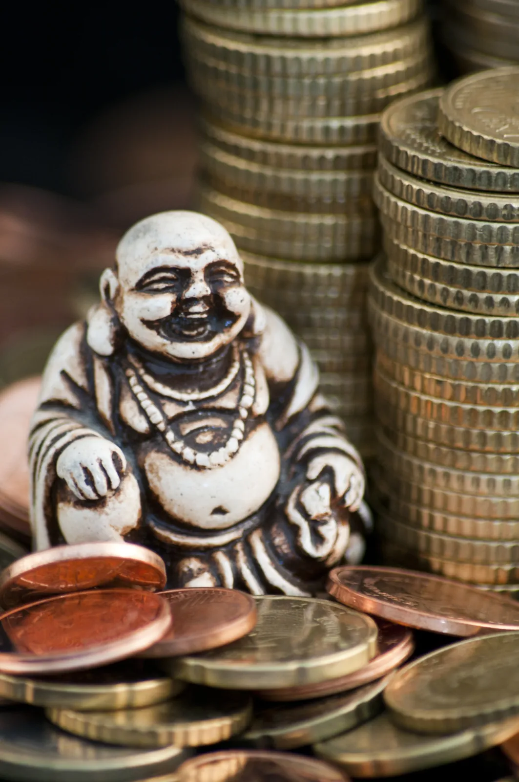 Stacks of coins beside a small smiling figurine