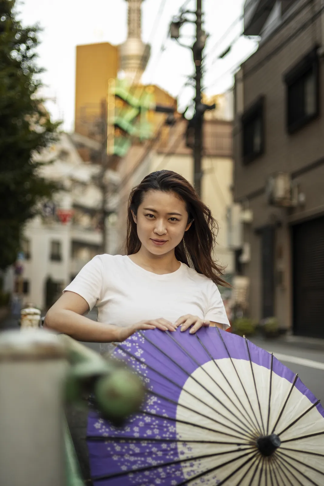 A woman holding a paper parasol on a city street